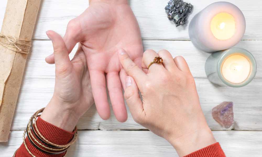 a palmist doing a palm reading. There are crystals and candles on the table